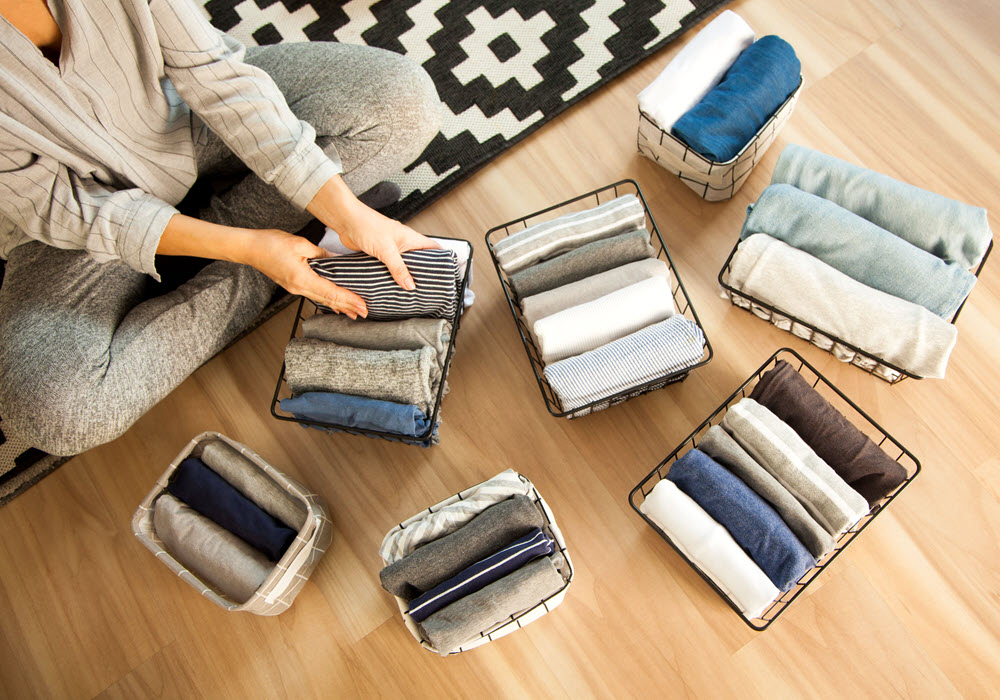 Woman folding and organizing clothes into baskets.