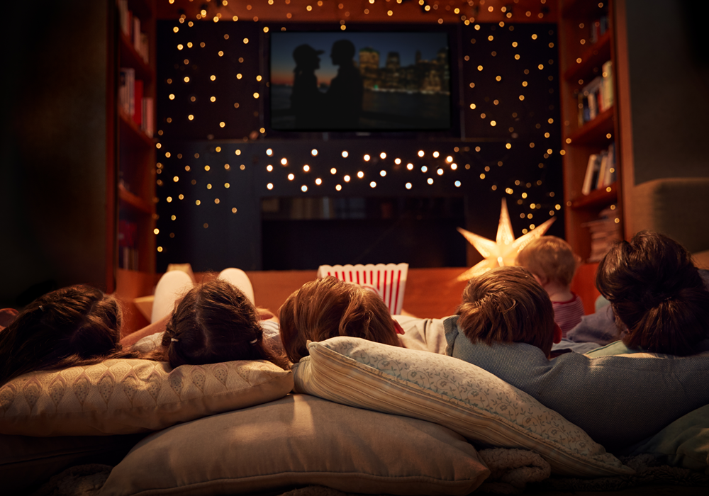 A family in bed watching a holiday movie in the dark.