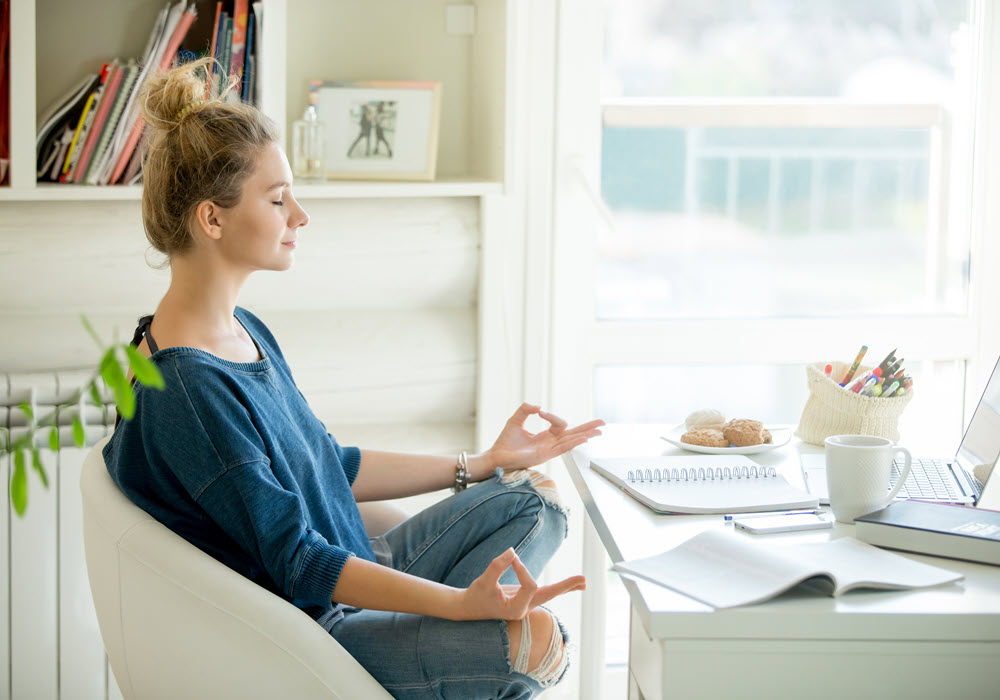 Woman meditating in her apartment home.