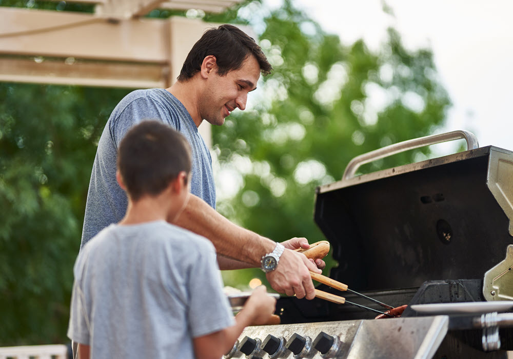 Dad barbequing with son using an apartment amenity.