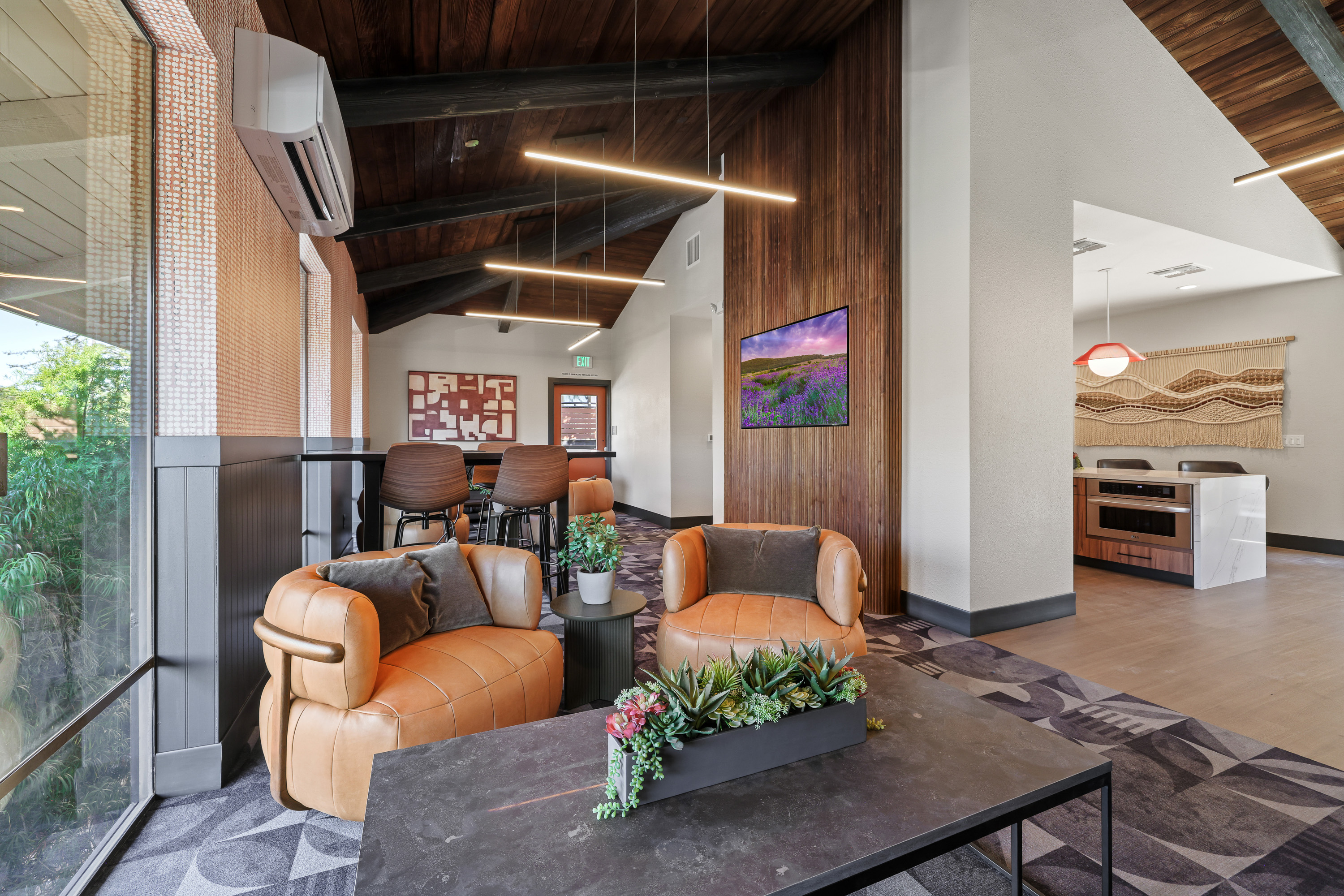 Renovated Lafayette Highlands clubroom with leather lounge chairs, wood-paneled ceilings, modern lighting, and kitchenette seating.